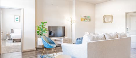 Una sala de estar moderna con un sofá, un televisor, un ventilador de techo y una planta.