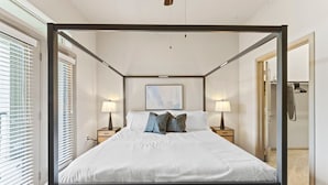 A four-poster bed with white bedding, two bedside lamps, and a framed picture on the wall. - Elegant 2BR King Suite Fast Wifi 8 min to DT (Austin)