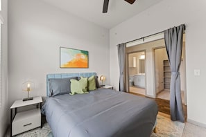 A bedroom with a bed, nightstands, a painting, and a view into the bathroom. - Elegant 2BR King Suite Fast Wifi 8 min to DT (Austin)