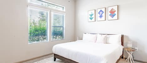 Un dormitorio con cama, ventana con persianas, mesita de noche y decoración en la pared.