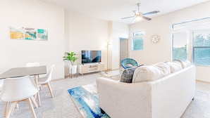 A modern living room with a sofa, a dining table with chairs, a TV, and artwork on the walls. - Spacious 2BR King Beds Suite 8 Min to Downtown (Austin)