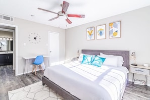 A bedroom with a bed, a desk, a chair, a ceiling fan, and three wall art pieces. - Trendy Soco 1BR Suite King bed Fast Wifi w Pool (Austin)