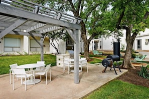 An outdoor patio with a pergola, a barbecue grill, and a dining area with white chairs and tables. - Trendy Soco 1BR Suite King bed Fast Wifi w Pool (Austin)