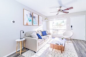 A modern living room with a sofa, coffee table, and a ceiling fan. - Trendy Soco 1BR Suite King bed Fast Wifi w Pool (Austin)
