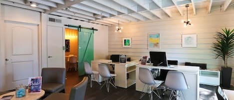 Un espacio de oficina moderno con un escritorio, sillas y una computadora. Hay una puerta y una planta en la habitación.