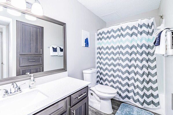 A bathroom with a white sink, a mirror, a toilet, and a shower curtain with a chevron pattern. - Trendy Soco 1BR Suite King bed Fast Wifi w Pool (Austin)