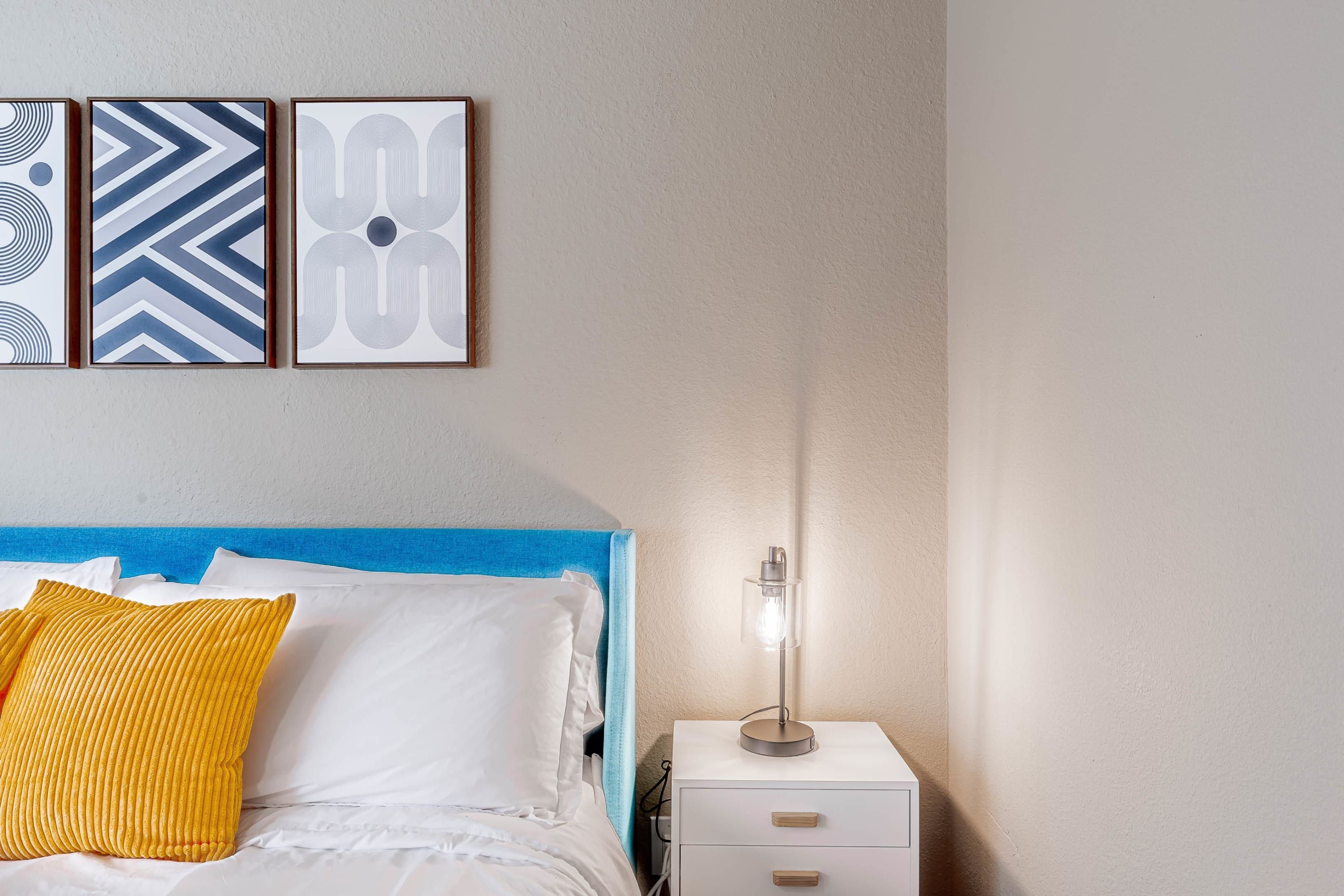 Une chambre à coucher avec un lit, une table de chevet et une lampe fixée au mur.