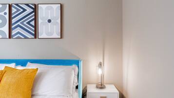 A bedroom with a bed, a nightstand, and a wall-mounted lamp.