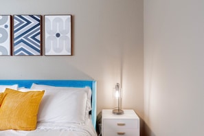A bedroom with a bed, a nightstand, and a wall-mounted lamp. - Spacious 1BR Close to Downtown w Fast Wifi w Pool (Austin)