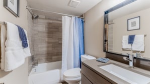 A bathroom with a bathtub, toilet, and sink. - King bed 1BR Close to Downtown w Fast Wifi w Pool (Austin)