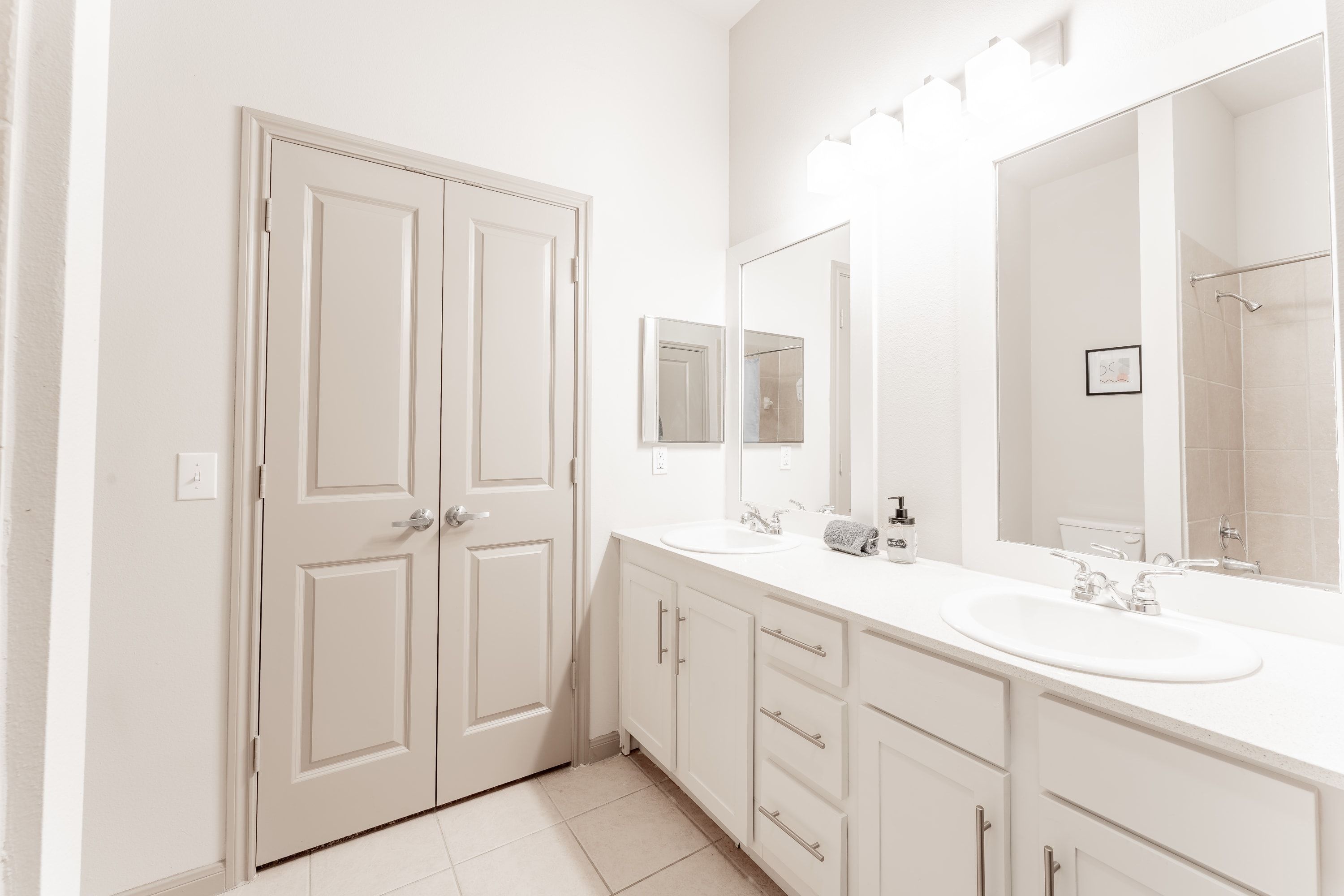A bathroom with two sinks, a large mirror, and a shower area.