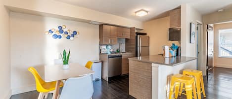 A modern kitchen with a central island, wooden cabinets, and a built-in dishwasher.