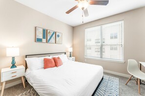 A hotel room with a bed, two bedside tables, a ceiling fan, a window with blinds, and artwork on the wall. - Trendy Soco 2BR King Suite w Gympickleballlaundry (Austin)