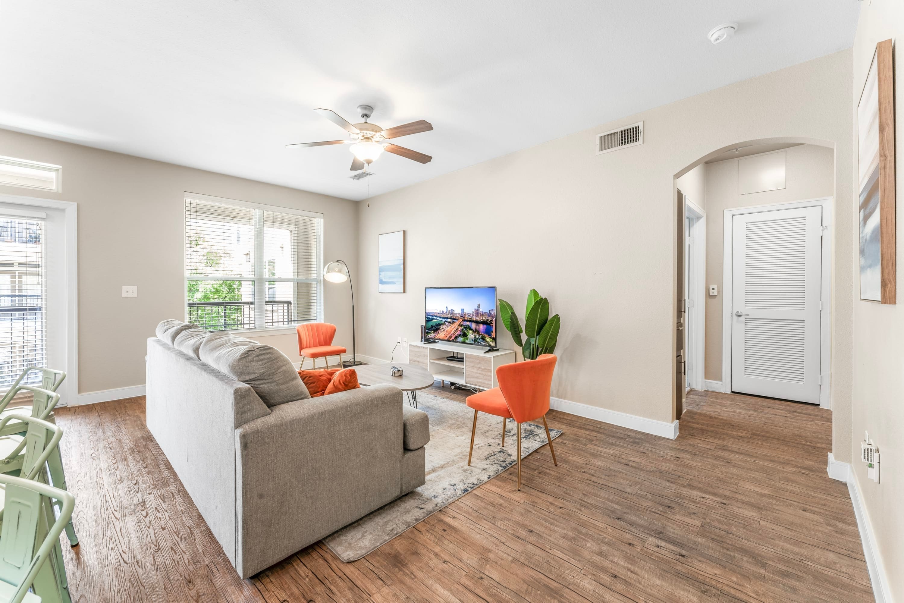 A modern living room with a sofa, a television, and a ceiling fan.