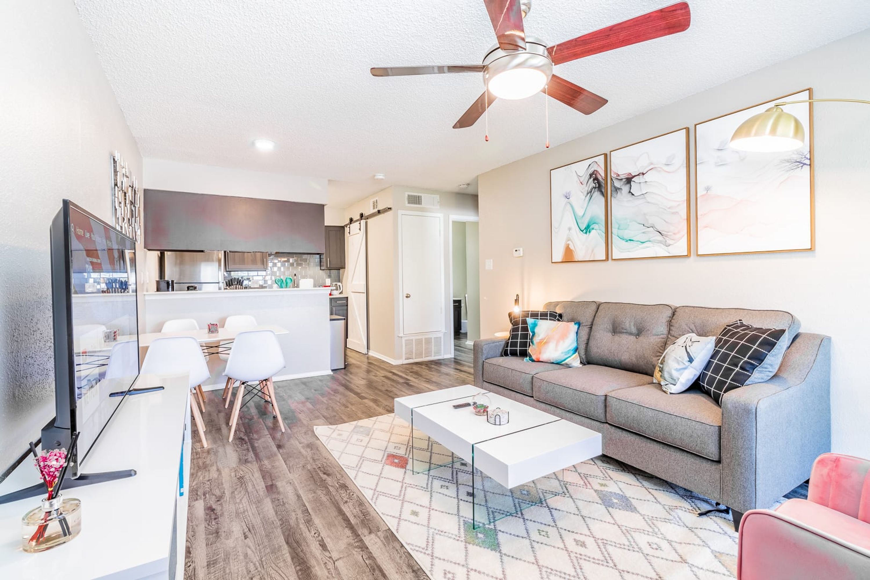A modern living room with a grey sofa, white coffee table, and a ceiling fan.