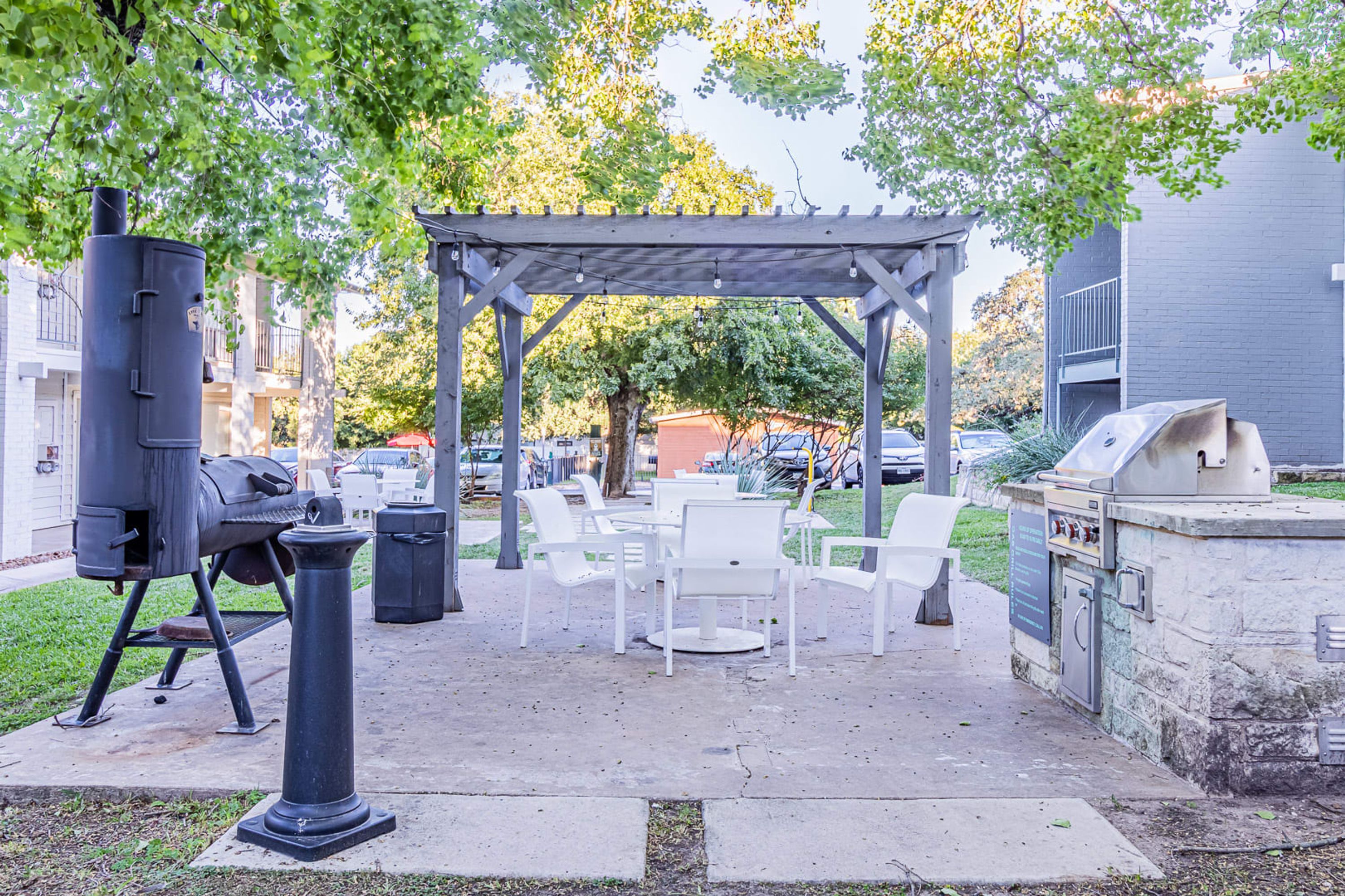 An outdoor patio with a grill, seating area, and a pergola.