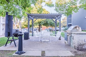 En uteplats med grill, sittplats och en pergola.