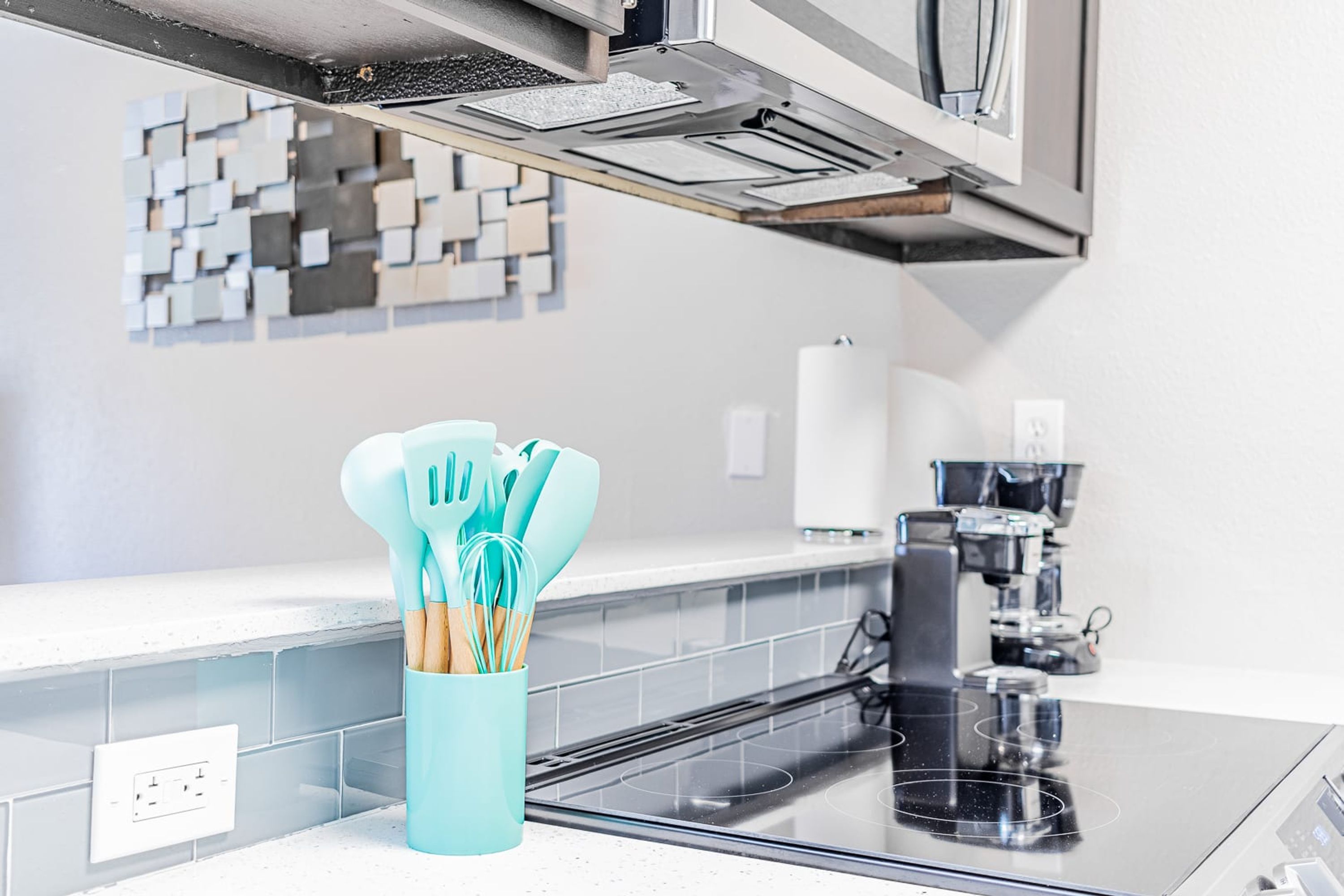 A kitchen with a modern stove, a coffee maker, and a utensil holder on the counter.