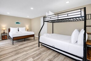 Una habitación con literas, una cama individual, una mesita de noche y una lámpara fijada a la pared.