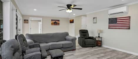 A living room with a grey sectional sofa, a recliner, a ceiling fan, and an American flag on the wall.