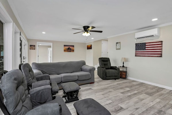 A living room with a grey sectional sofa, a recliner, a ceiling fan, and an American flag on the wall.