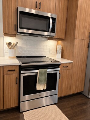 A kitchen with a stainless steel microwave, oven, and stovetop. - The Westside Retreat 2BD|2BTH (Atlanta)