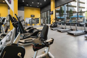 A gym with various exercise equipment, including treadmills and weight machines, and a large window providing a view of the outdoors. - The Westside Retreat 2BD|2BTH (Atlanta)