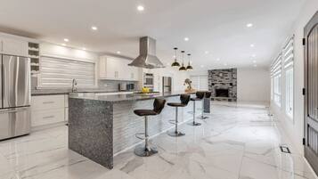 A modern kitchen with a central island, bar stools, stainless steel appliances, and a fireplace.