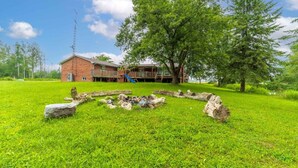 A grassy area with a brick building, a playground, and a large tree.