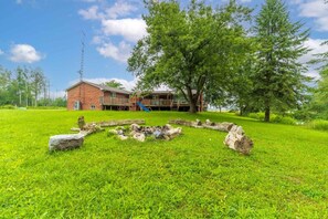 A grassy area with a brick building, a playground, and a large tree.