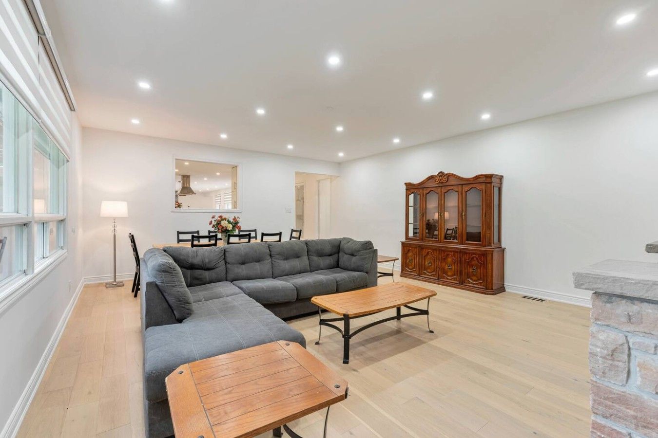 Ein geräumiges Wohnzimmer mit einem Ecksofa, einem Couchtisch aus Holz und einer traditionellen Holzkommode.