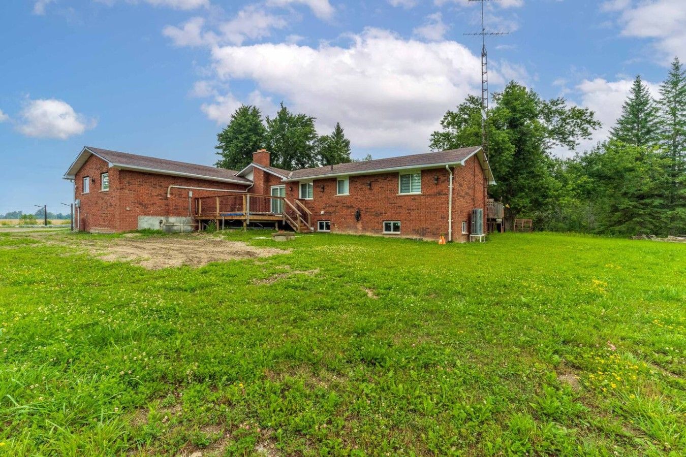 A two-story brick building with a large grassy yard and a wooden deck.