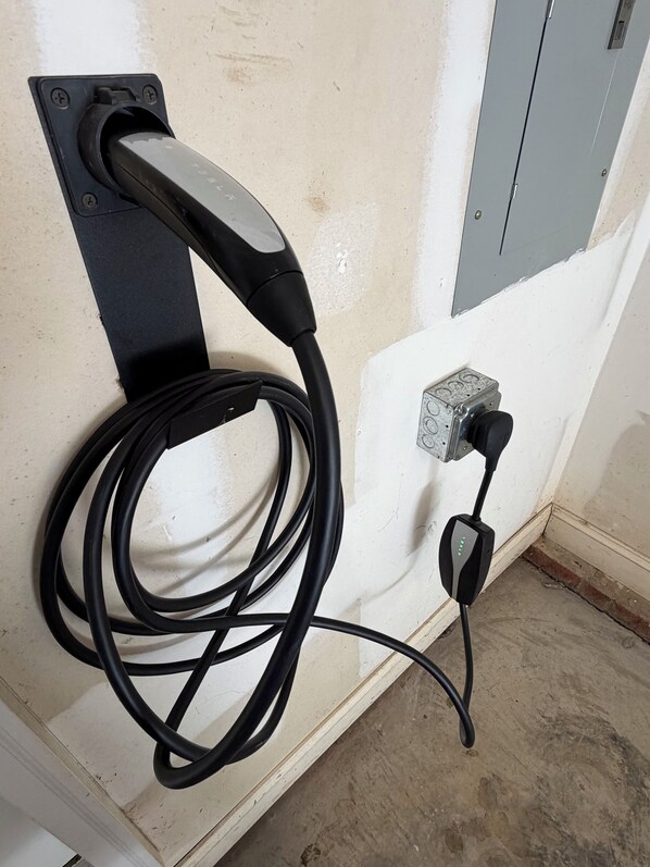 A wall-mounted electrical outlet with a cable connected to a power strip.