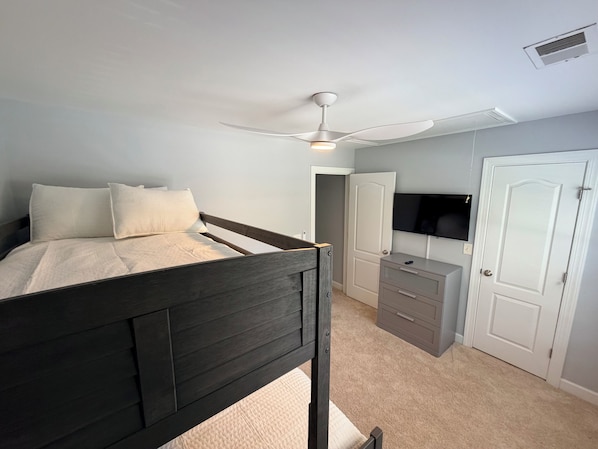 Een slaapkamer met een bed, een plafondventilator, een televisie en een kledingkast.