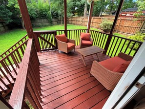 A wooden deck with wicker furniture and a table.