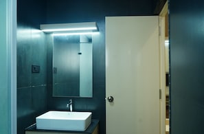 A bathroom with a white sink, a mirror, and a door. - Kristal Grand (Bengaluru)