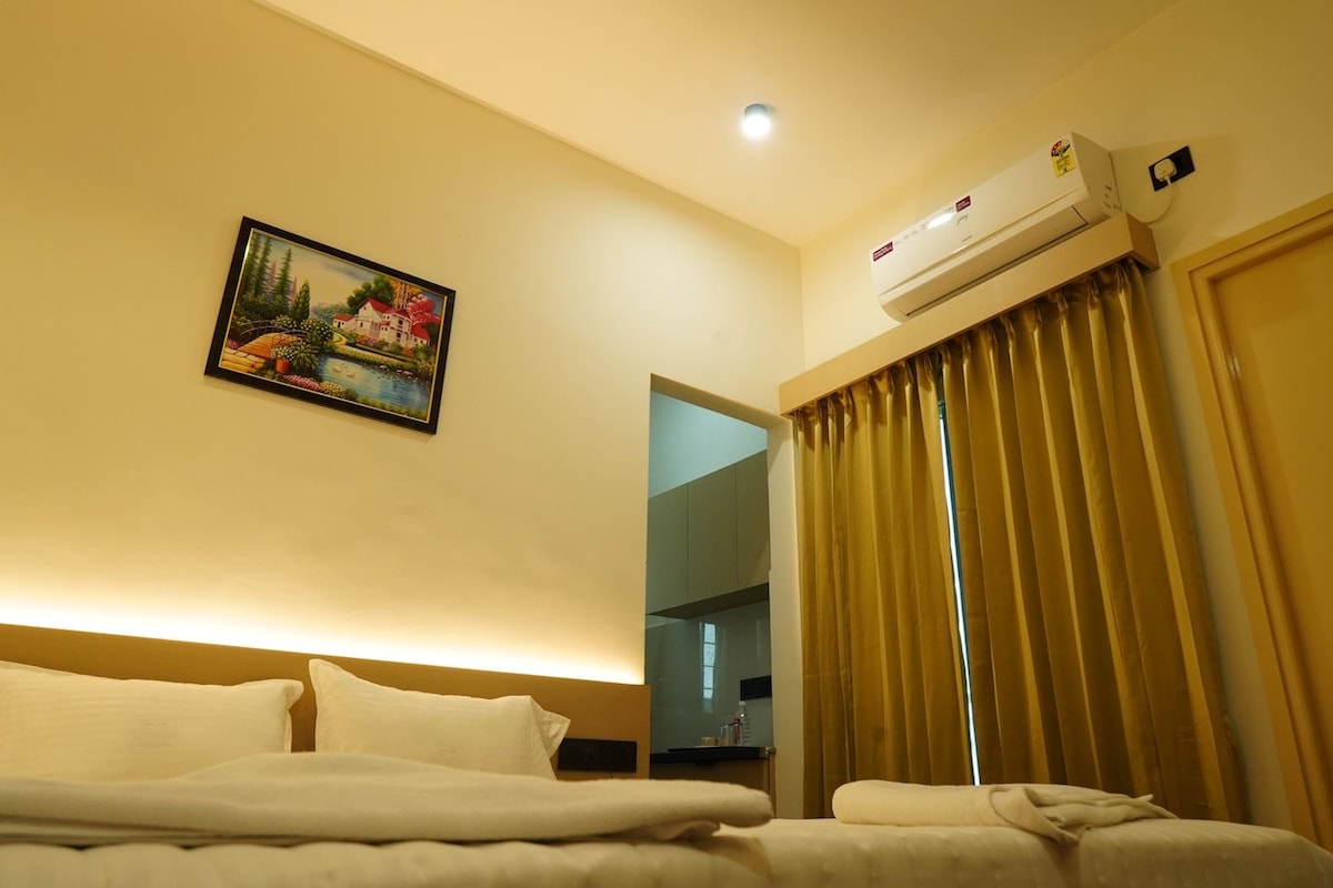 A hotel room with a bed, a painting, an air conditioning unit, and a window with curtains.