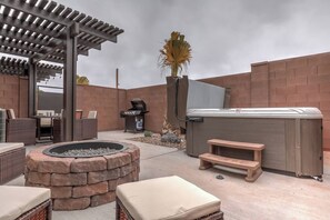 Une terrasse extérieure avec un foyer, des sièges, un barbecue et un jacuzzi.