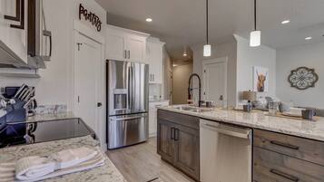 A modern kitchen with stainless steel appliances, a marble countertop, and a wooden cabinet.