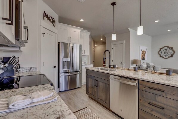 A modern kitchen with stainless steel appliances, a marble countertop, and a wooden cabinet.