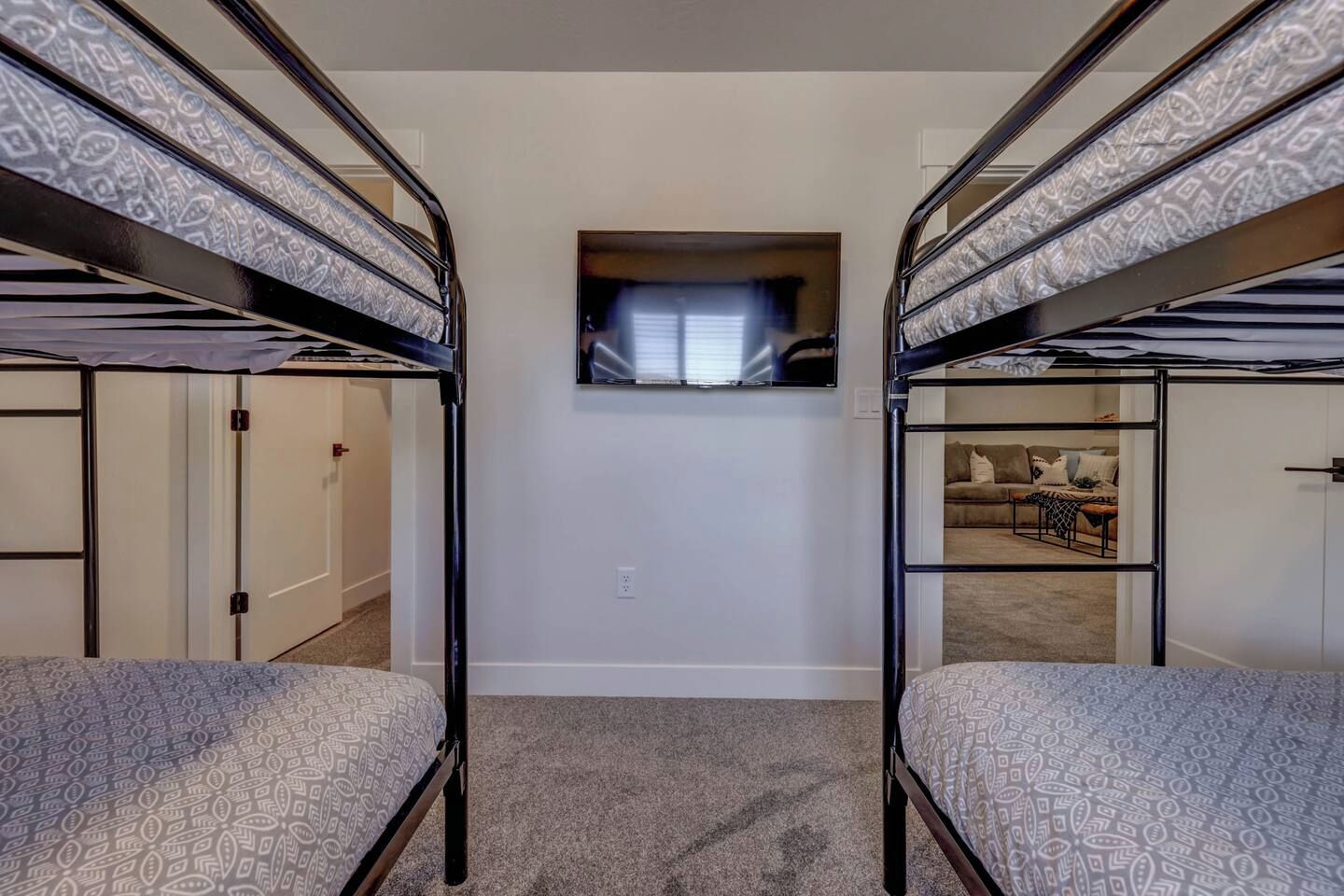 Ein Zimmer mit Etagenbetten, einem Fernseher und Blick in einen Wohnbereich.