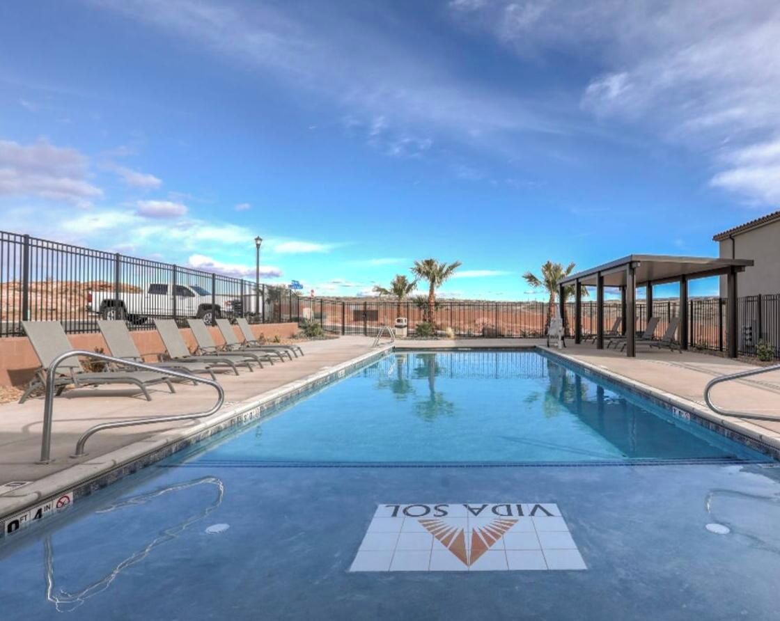 A swimming pool with lounge chairs and a desert landscape in the background.