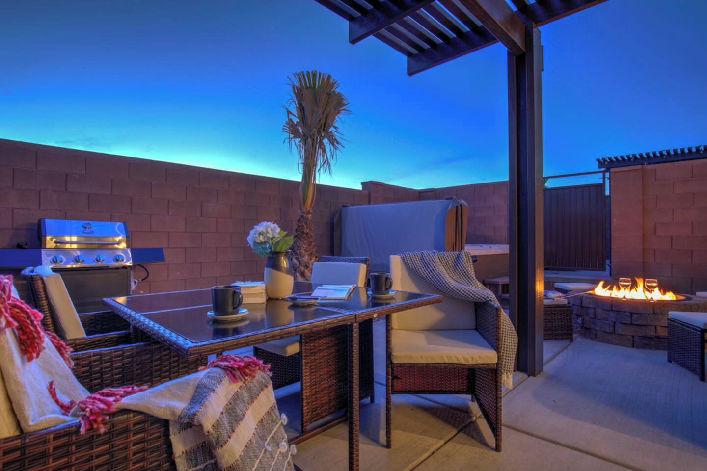 An outdoor patio with a grill, seating, and a fire pit.