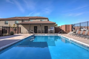 Une piscine avec un poste de surveillance pour les sauveteurs, des chaises longues et un bâtiment doté d’un toit en tuiles.