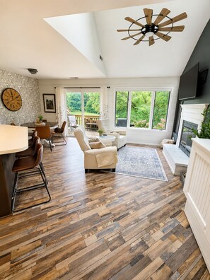 A spacious living area with a wooden floor, a ceiling fan, and a fireplace. - Fairway Stay: Golf Views, Pool & Near Eagle Ridge (Galena)