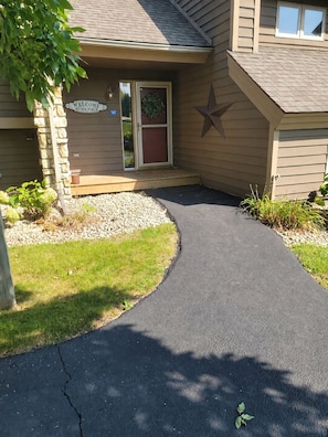A house entrance with a welcome sign, a star decoration, and a gravel driveway. - Fairway Stay: Golf Views, Pool & Near Eagle Ridge (Galena)