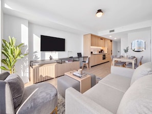 Een moderne woonkamer met een flatscreen televisie, een eethoek en een keuken.