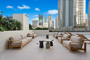 A rooftop lounge with outdoor seating and a city view. - Luxury Worldcenter Condo - Pool - Gym - Parking (Miami)