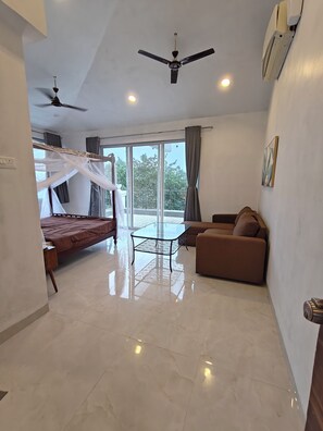 A modern bedroom with a bed, a glass table, a sofa, and a ceiling fan. - Spacious 4-bedroom bungalow in lovely Lonavla with AC (lonavla)