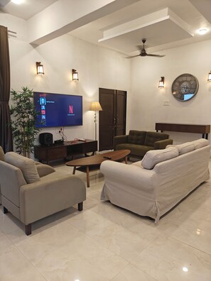 A modern living room with a flat-screen TV, sofa, armchair, and a coffee table.